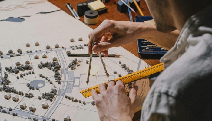Architect meticulously working on a detailed scale model with compass and ruler.